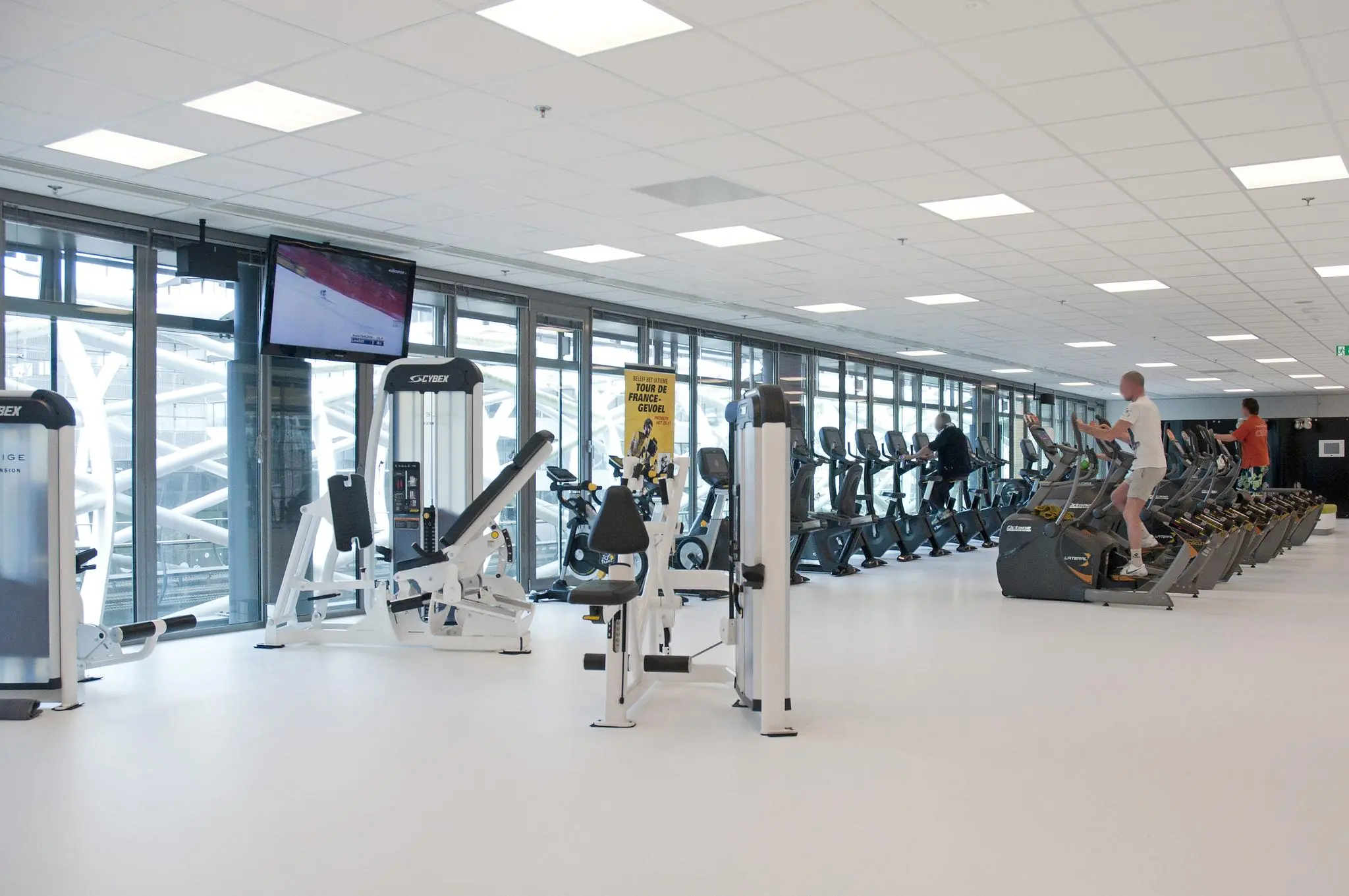 Moderne fitnessruimte aan de Prinses Beatrixlaan met cardio- en krachtapparatuur en sporters in actie.
